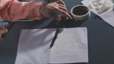 Masanın üzerinde bir kalem olan beyaz bir kağıt parçasıyla kadın elleri