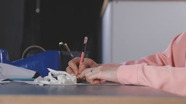 Genç bir kadın beyaz bir deftere yazıyor..