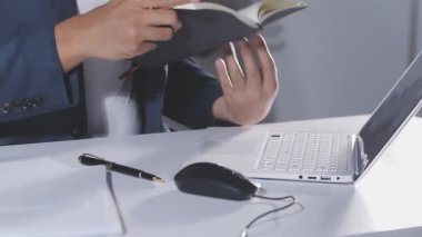 İşadamı ofiste dizüstü bilgisayar ve kalemle çalışıyor.