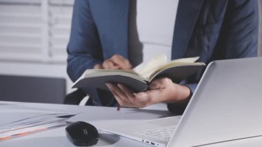 İş adamı elinde bir dizüstü bilgisayar ve defterle çalışıyor.