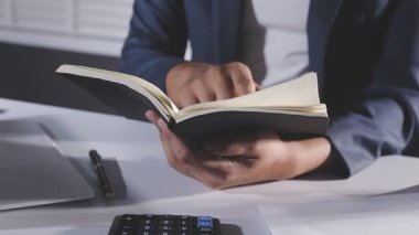 Adam ofiste defter ve bilgisayarla çalışıyor.