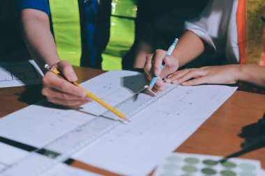 Endüstriyel mühendislerden oluşan bir ekip, fabrikadaki masada bulunan makine planlarını analiz ediyor. Fabrikada ya da üretim tesisinde çalışıyorum..