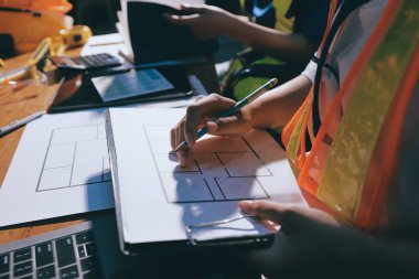 Endüstriyel mühendislerden oluşan bir ekip, fabrikadaki masada bulunan makine planlarını analiz ediyor. Fabrikada ya da üretim tesisinde çalışıyorum..