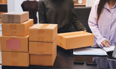 Küçük işletmeler kurma portresi KOBİ sahipleri ve iki Asyalı kadın online siparişleri kontrol ediyor. Ev işlerinde çalışan kutucuklarla çalışan ürünleri satıyorlar.