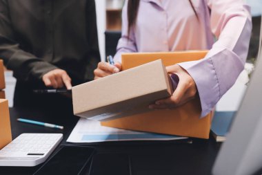 Küçük işletmeler kurma portresi KOBİ sahipleri ve iki Asyalı kadın online siparişleri kontrol ediyor. Ev işlerinde çalışan kutucuklarla çalışan ürünleri satıyorlar.