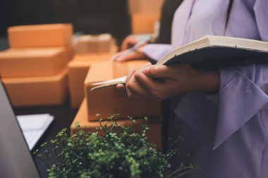 Küçük işletmeler kurma portresi KOBİ sahipleri ve iki Asyalı kadın online siparişleri kontrol ediyor. Ev işlerinde çalışan kutucuklarla çalışan ürünleri satıyorlar.