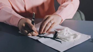 a female hand draws a white paper on a table