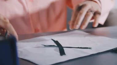 close - up of a woman 's hands cutting the fabric with a scissors in the studio.