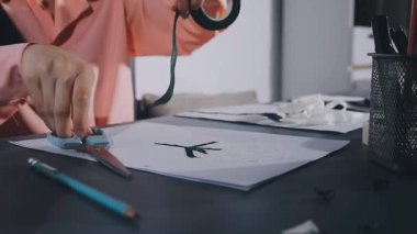 close - up of female hands in white clothes making handmade pattern from a leather bag.