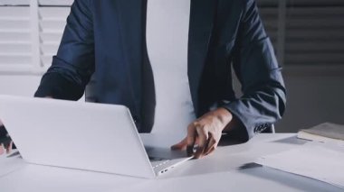 Genç işadamı merkez ofiste dizüstü bilgisayarla çalışıyor.