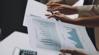 businessman using a tablet computer and pointing at graph on his desk in office