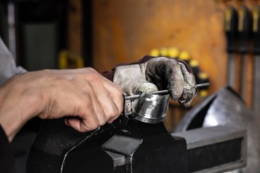 Male metal worker constructing or repairing piece of metal assembly. Man hands working with metal parts in a workshop clipart