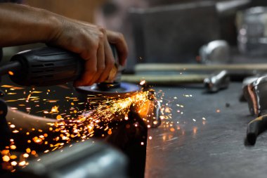 Adam donanım bir atölyede metal parçalar ile açı değirmeni tedavi eller. Parlatma ve ortaçağ zırh takım elbise parçası sonuçlandırılması erkek demir ustası