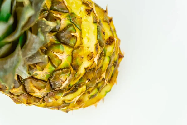 One sliced pineapple on isolated white background, shot from above. Top view of ripe fresh pineapple standing on white table