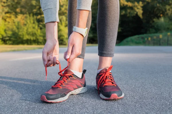 Lacing up running shoes. Close-up of woman hands that lace up trainers outdoors in a park