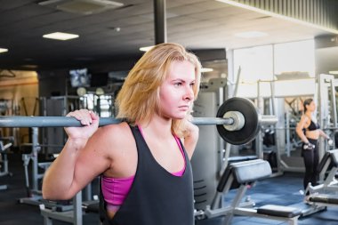 Genç kadın heavylifting egzersiz yaparak spor salonunda yerleştirmek. Barbell ile çalışma dışarı bir fitness salonu, kadın atlet