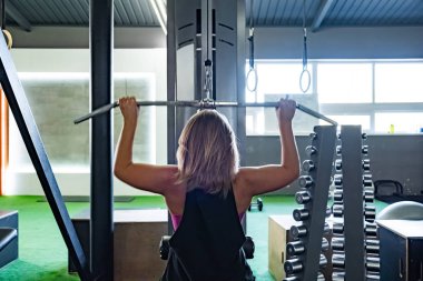Genç kadın spor salonunda ağırlık makine ile açılan egzersiz yaparak yerleştirmek. Kadın atlet ağırlıklı makara makine ile çalışma dışarı bir fitness salonu