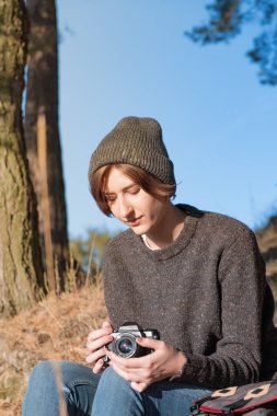 Açık havada güzel sonbahar havanın tadını. Güneşli bir öğleden sonra genç kadın uzun yürüyüşe çıkan kimse ile a fotoğraf makinesi çam ağaçlarının altında oturur