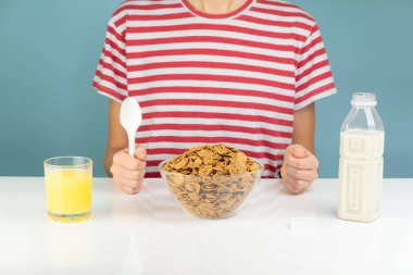 Breakfast with whole grain cereals, milk and juice. Illustrative minimalistic image of healthy vegetarian food on the table and hungry person