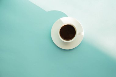 Fincan kakao yeşil masada, üstten görünüm kahve buğulaması. Soluk mavi-yeşil zemin üzerine sıcak espresso içki soyut fotoğraf.