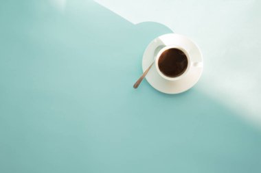 Fincan kakao yeşil masada, üstten görünüm kahve buğulaması. Soluk mavi-yeşil zemin üzerine sıcak espresso içki soyut fotoğraf.