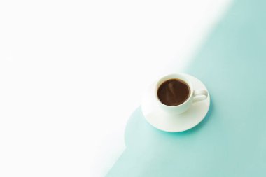 Turkuaz mavi masada kahve buğulaması Kupası. Soluk mavi-yeşil zemin üzerine sıcak espresso içki soyut fotoğraf.