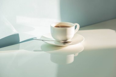 Fincan kahve parlak güneş ışığı altında deniz yeşil zemin üzerine buğulaması. Sıcak espresso içki soluk mavi-yeşil masa ve duvar soyut fotoğraf