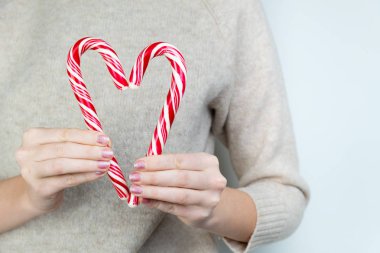 Sadaka kavramı: kişi kalp şekil verme iki şekerler tutar. İki beyaz ve kırmızı Noel şeker kalp kurdu.