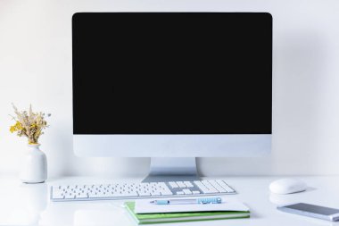Masaüstü bilgisayar ile temiz ve minimalist Ofis çalışma yer. Temiz beyaz masa üstünde Pc, cep telefonu, kağıtları ve sayısal klavye önden görünüm