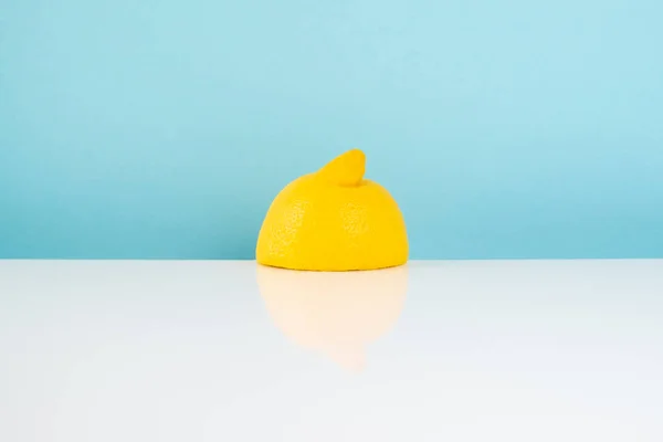 Half of lemon on white table. Minimalistic image of yellow citrus on bright  studio background