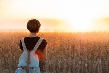 Arkadan aydınlatmalı parlak Günbatımı keyfi bir kadın figürü. Güneş ışığı alan, akşam duran kadın kişi