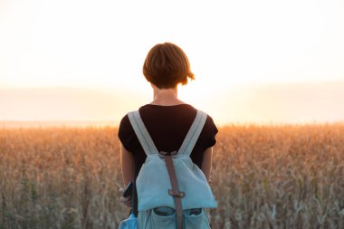Arkadan aydınlatmalı parlak Günbatımı keyfi bir kadın figürü. Güneş ışığı alan, akşam duran kadın kişi