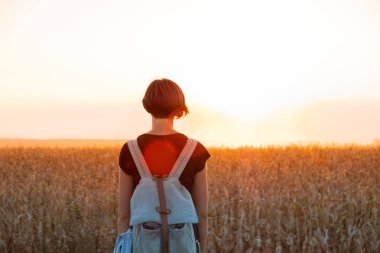 Arkadan aydınlatmalı parlak Günbatımı keyfi bir kadın figürü. Güneş ışığı alan, akşam duran kadın kişi