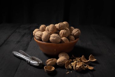 Koyu arka plan üzerine bir kase içinde ceviz. Koyu tonlu görüntü fındık siyah rustik masa, sanatsal ışık ve gölge tekniği