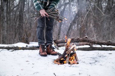 Bir kamp ateşi karlı bir ormanda yapma. Bir kış günü ormanda ateşe yakın erkek kişi
