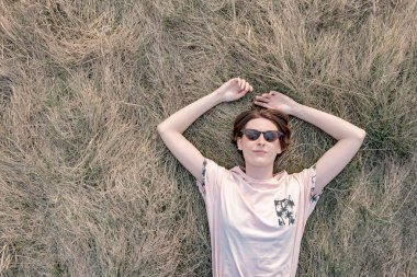 Genç kadın çimenlerin üzerinde dinleniyor baharın tadını çıkarıyor.