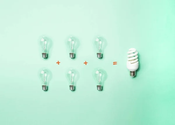 Tungsten light bulbs and energy-saving bulb on green background