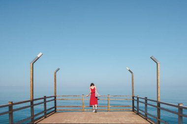 Güzel mavi denizin yanında iskelede durmak.