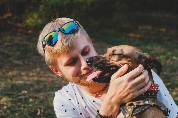 Human and dog friendship: young man hugs his dog outdoors — Stock Photo, Image