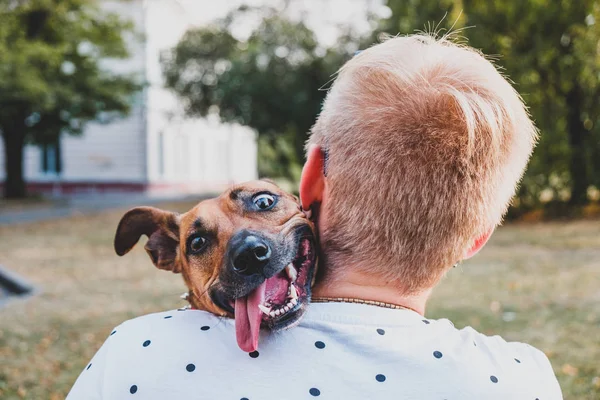 Människa och hund vänskap: ung man kramar hans rolig hund. — Stockfoto