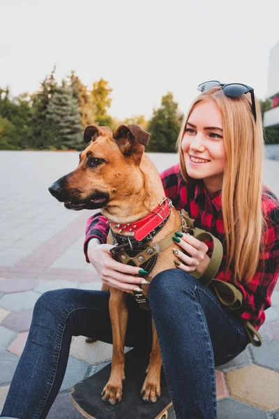 Teenage skater flicka kramas hennes hund i stadsmiljö. — Stockfoto
