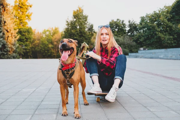 Gadis skater remaja memeluk anjingnya di lingkungan perkotaan . — Stok Foto
