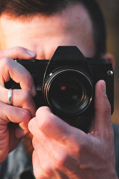 Close-up view of a black SLR camera in hands.