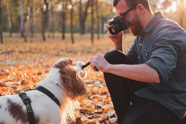 Mannen fotograferar sin hund i parken. — Stockfoto