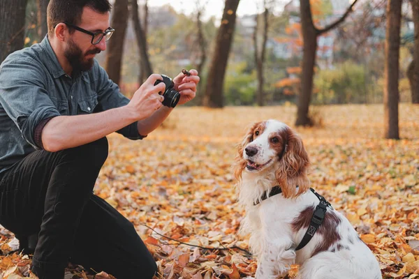 Mannen fotograferar sin hund i en park. — Stockfoto