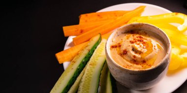 Humus sosu ve sebzeler tabakta, fotokopi alanı olan üst manzara. Sağlıklı vejetaryen yemeği veya aperatif, bitki bazlı ve vitamin açısından zengin yiyecekler.