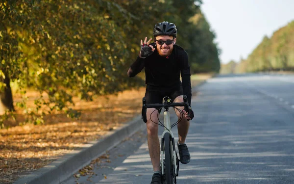 Smiling man on a road bicycle on the road. Cycling, training, feeling happy during physical activity on a gravel bicycle