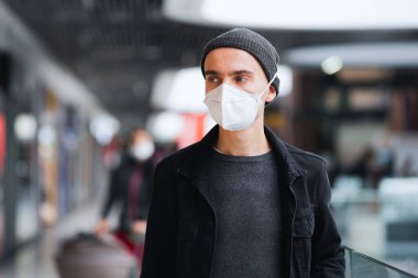 Koruyucu maskeli adam bir alışveriş merkezinde ya da yeraltı istasyonunda yürüyor. Salgın bir dünyada yaşamak, şehir manzarası