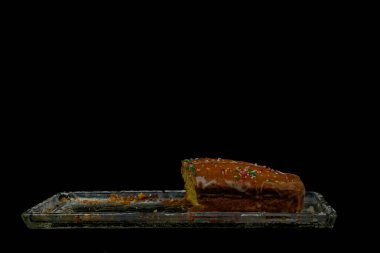 Dilimlenmiş keki şeker kremalı ve siyah üzerine izole edilmiş cam bir tabağa renkli şekerler serpiştirin. Yemek blogları, parti temaları, tatlı konseptleri ve reklamlar için mükemmel..