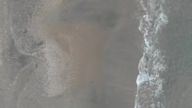 Üst hava manzarası yüzey okyanusunun hareketi ve zümrüt renkli suyun bol köpükle kuma çarpması.